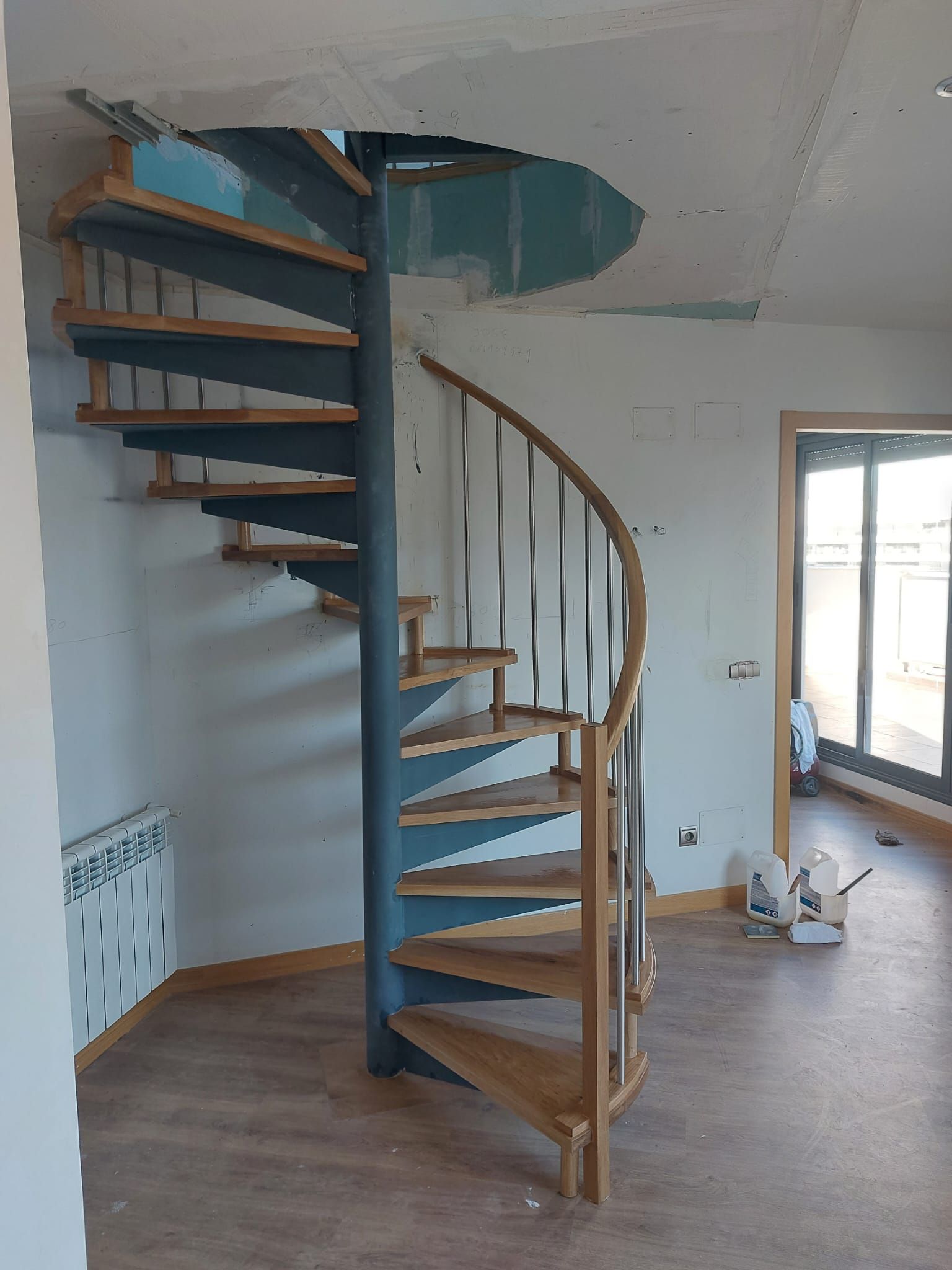 Una escalera de caracol con escalones de madera hay en una habitación.