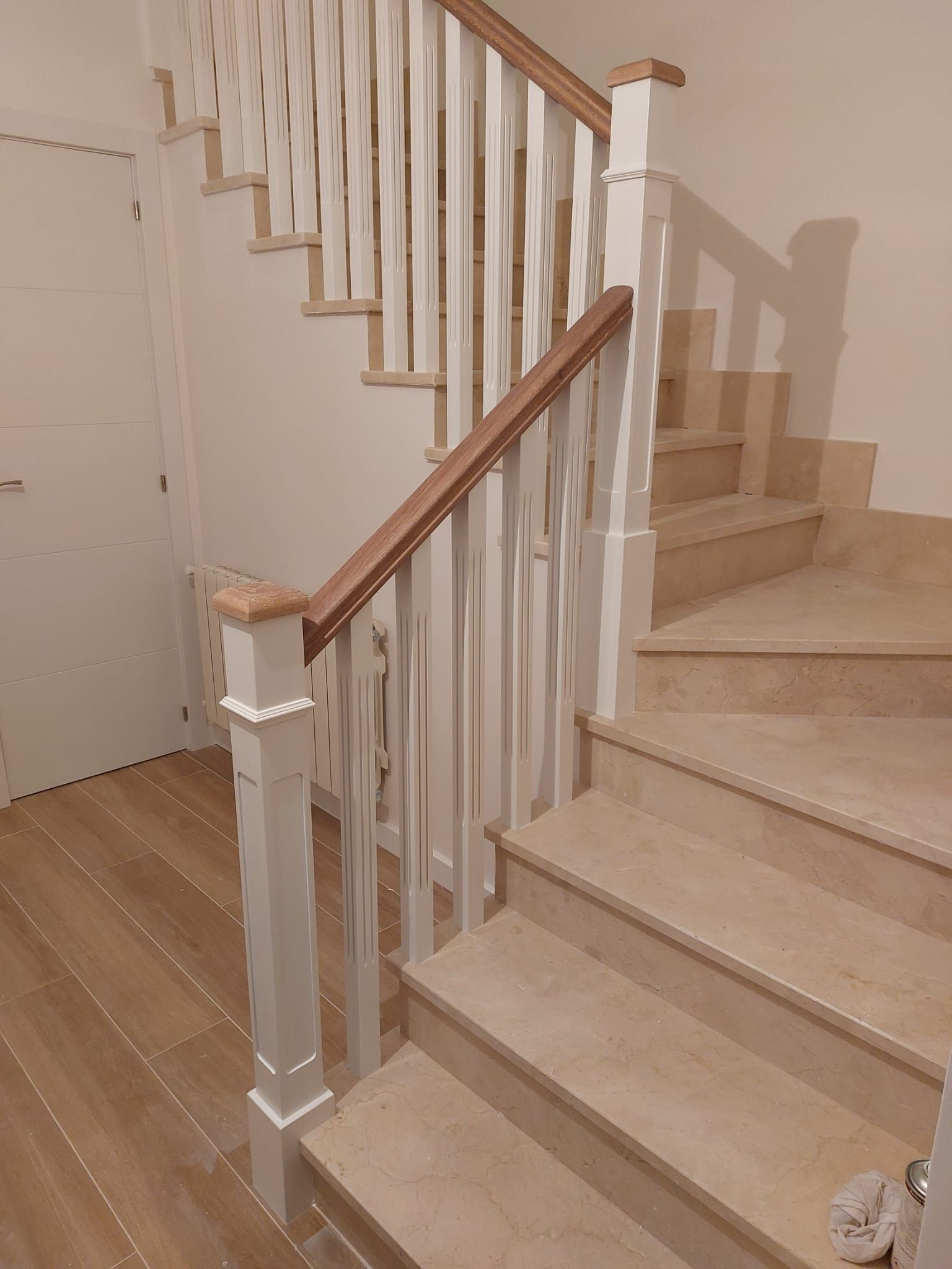 Una escalera de madera con barandilla blanca y pasamanos de madera.