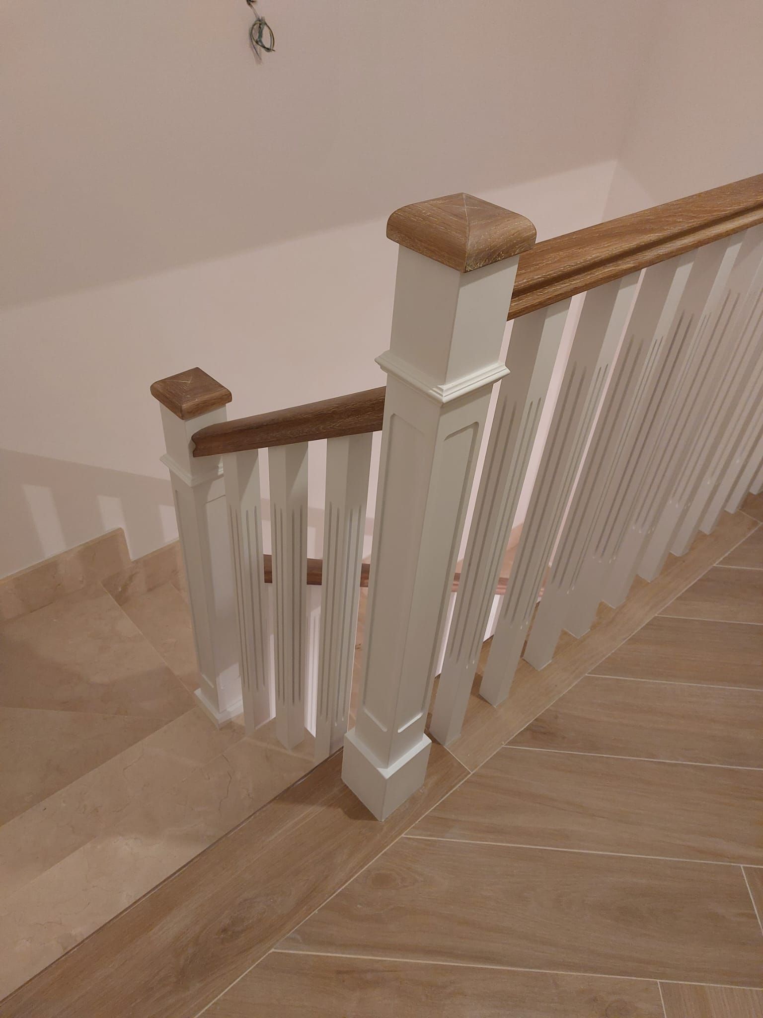 Una escalera con barandilla de madera y pasamanos blancos.