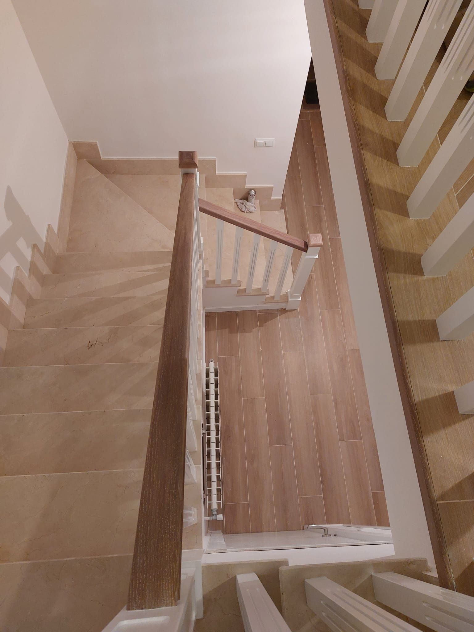 Una vista aérea de una escalera de madera con barandilla blanca.