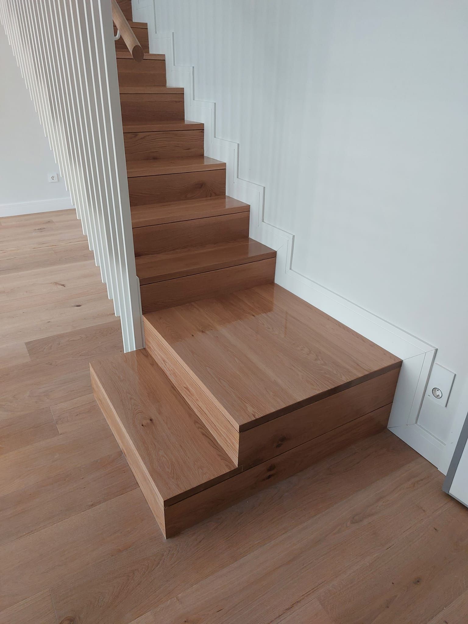 Una escalera de madera con barandilla blanca y suelo de madera.