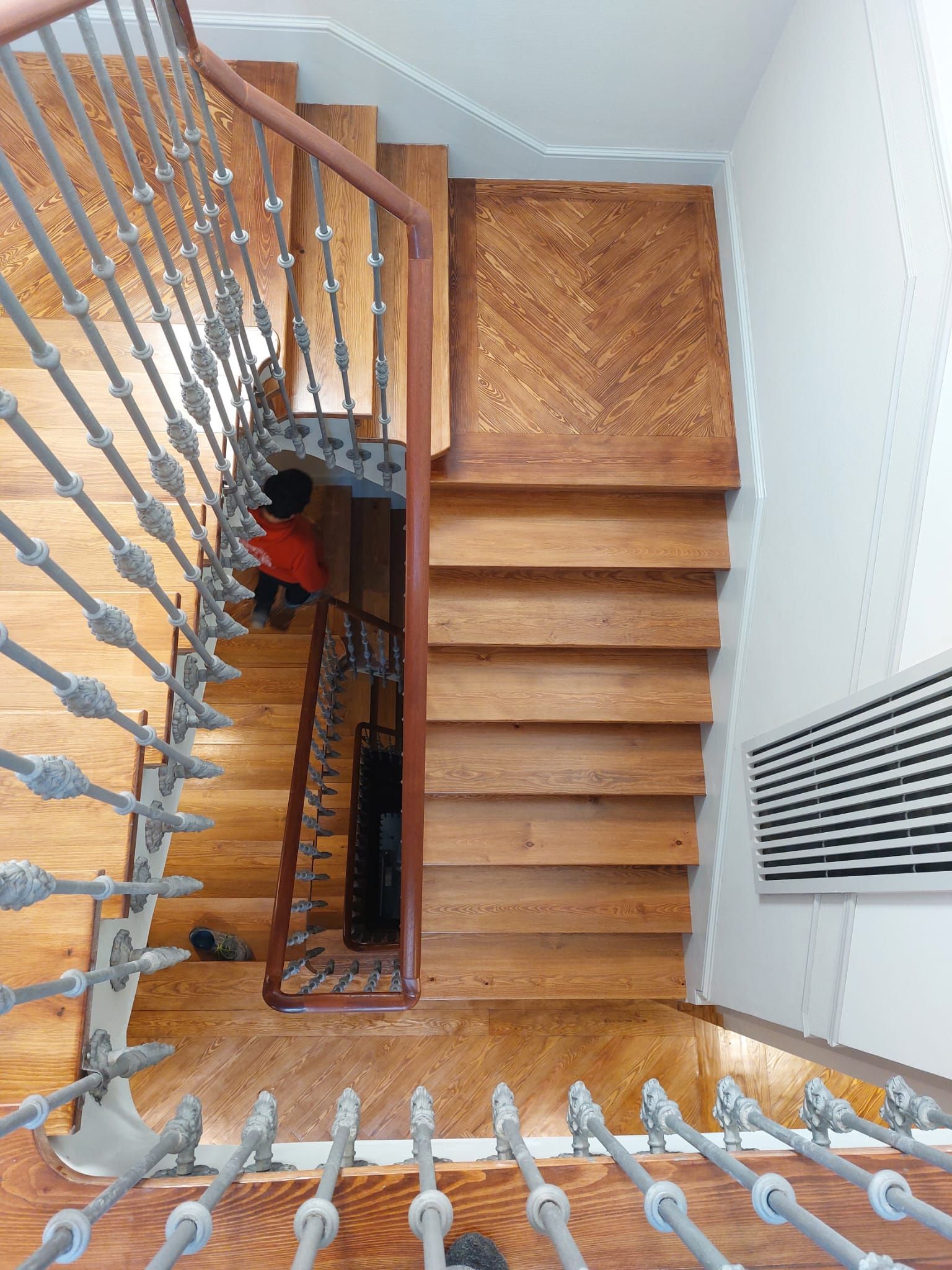 Una vista aérea de una escalera de madera con barandilla de hierro forjado.