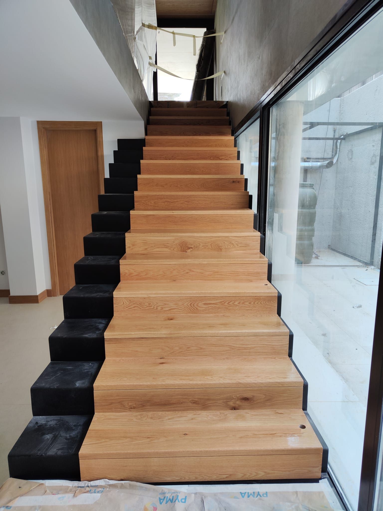 Una escalera de madera con escalones negros en un edificio.