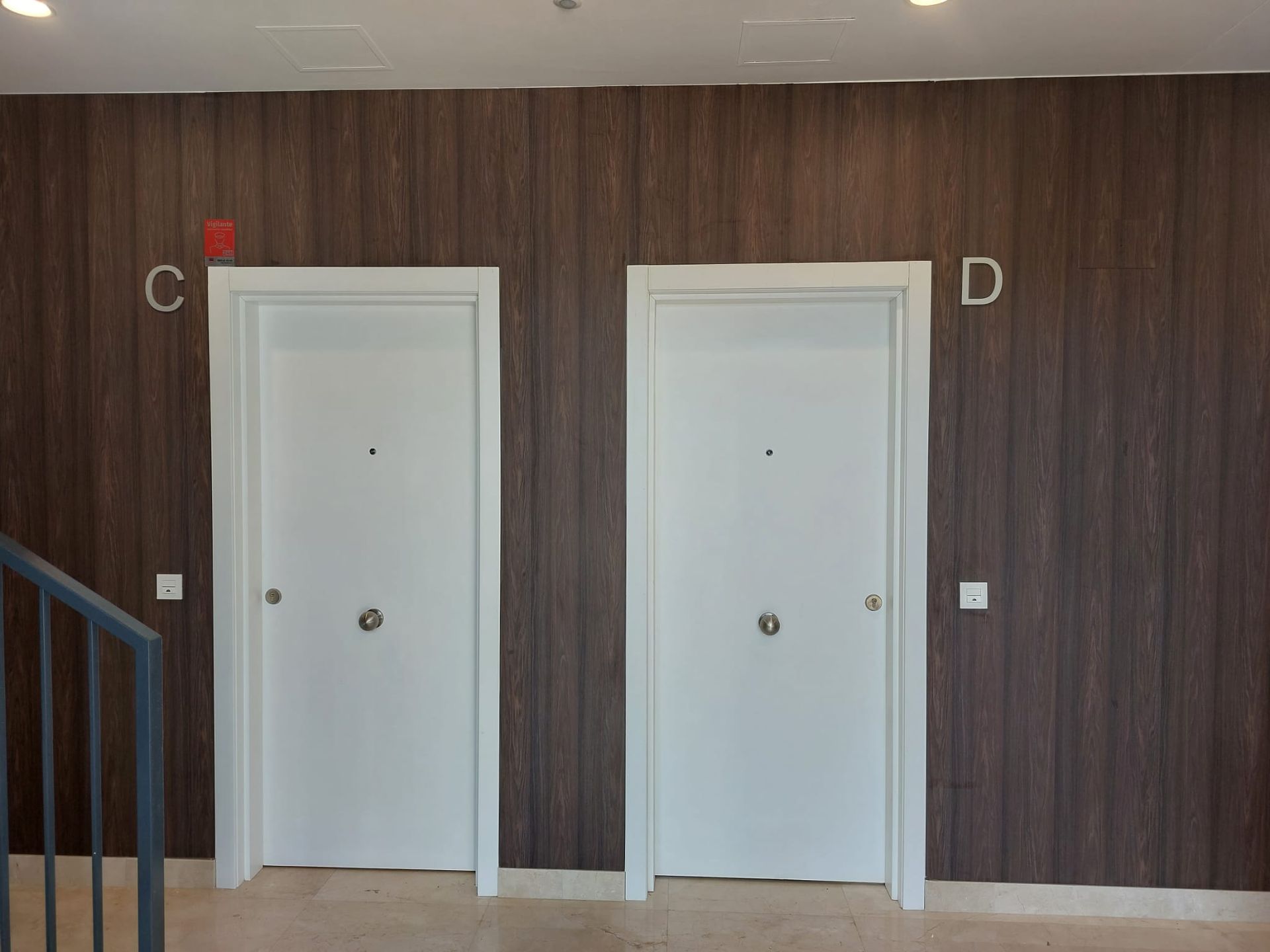 Un pasillo con dos puertas blancas y una pared de madera.