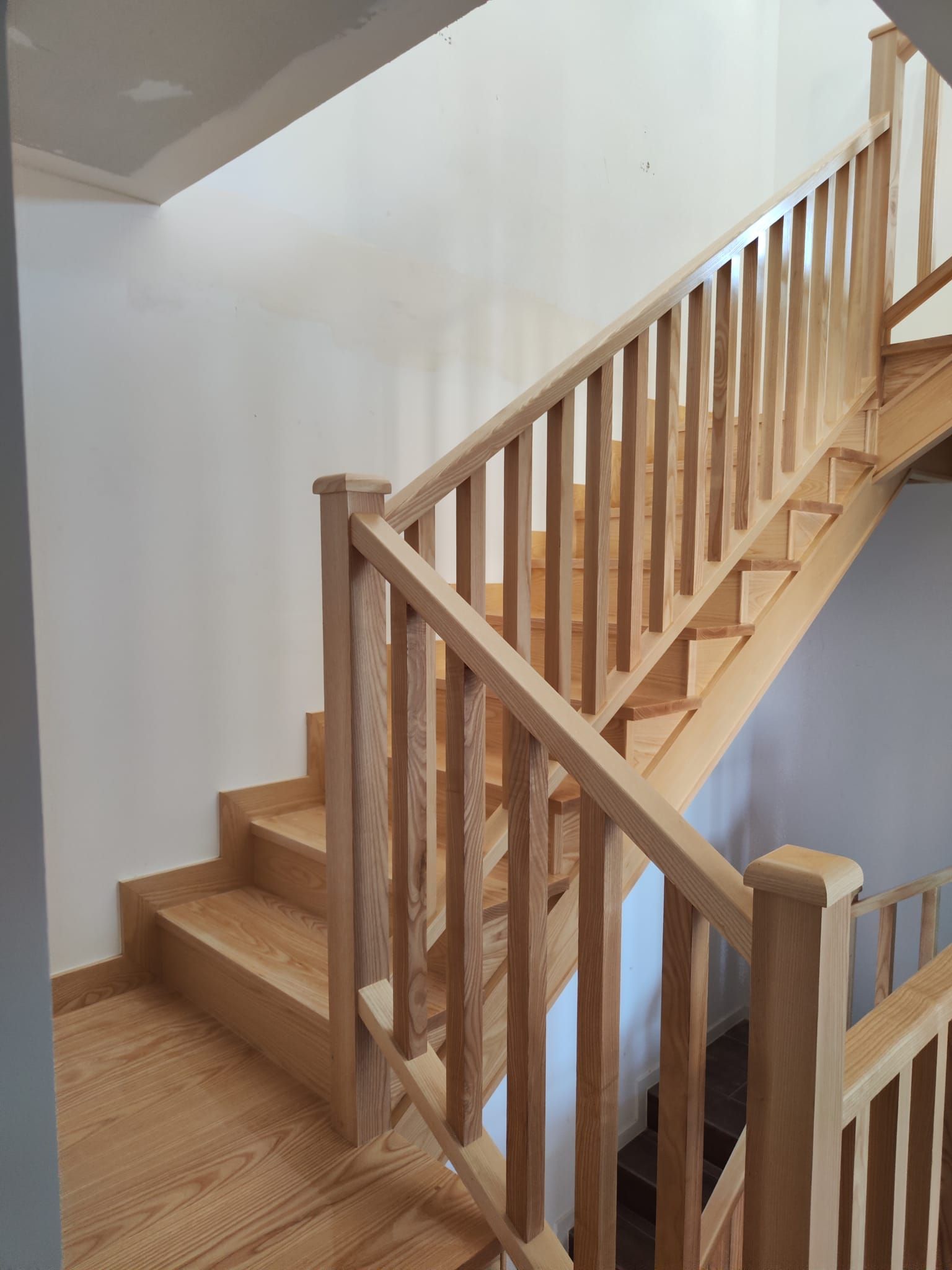 Una escalera de madera con barandilla de madera en una casa.