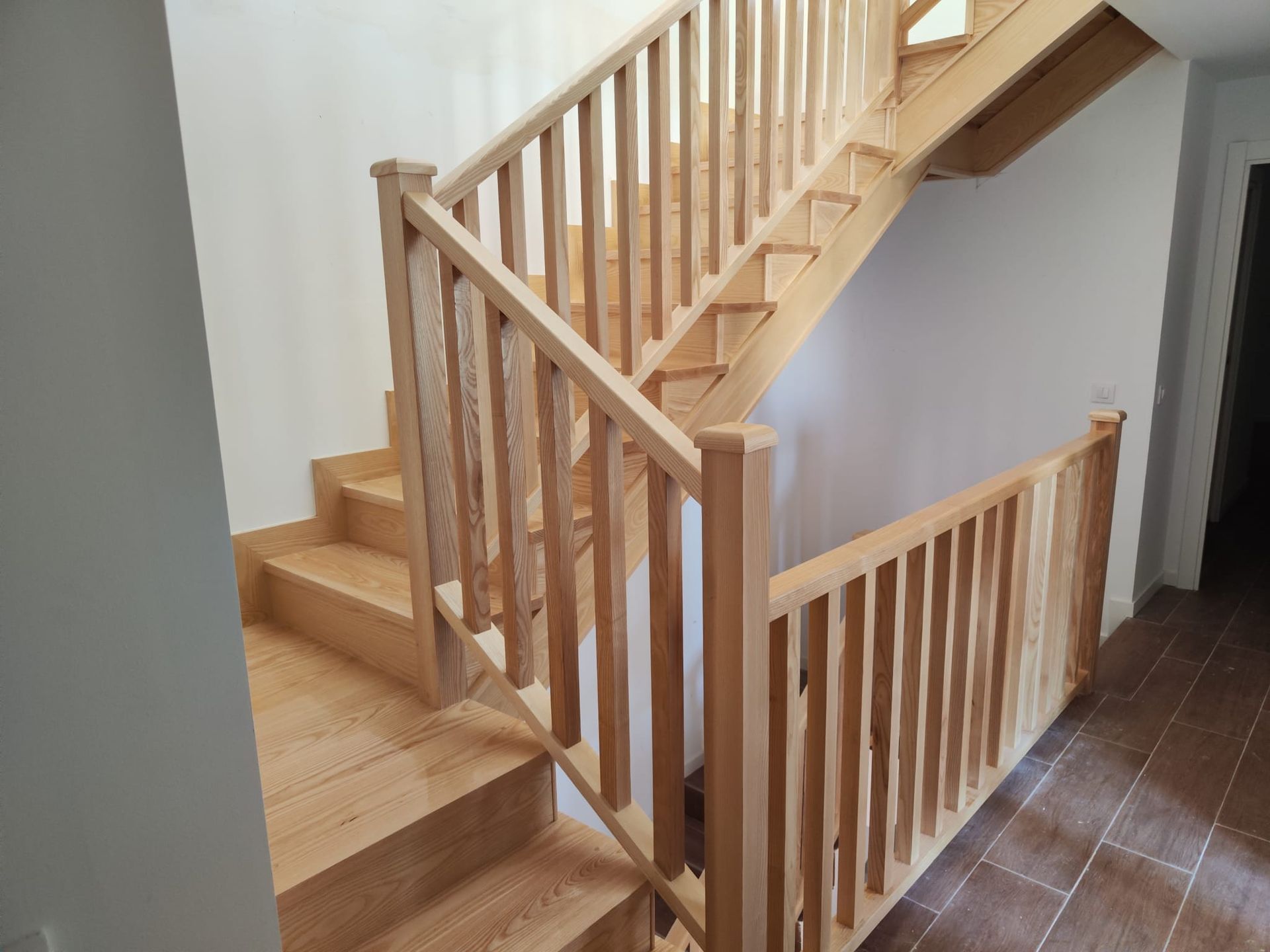 Una escalera de madera con barandilla de madera en un pasillo.