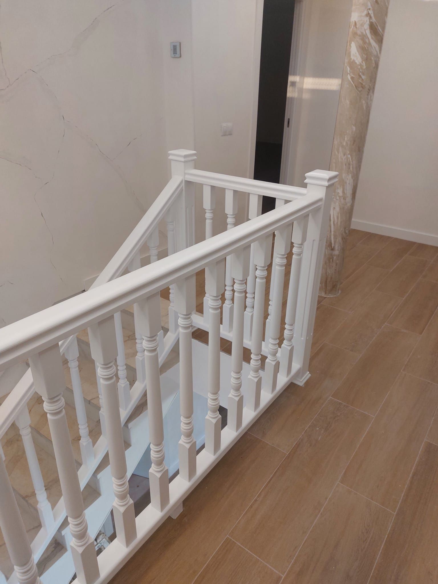 Una barandilla blanca en una escalera de madera en un pasillo.
