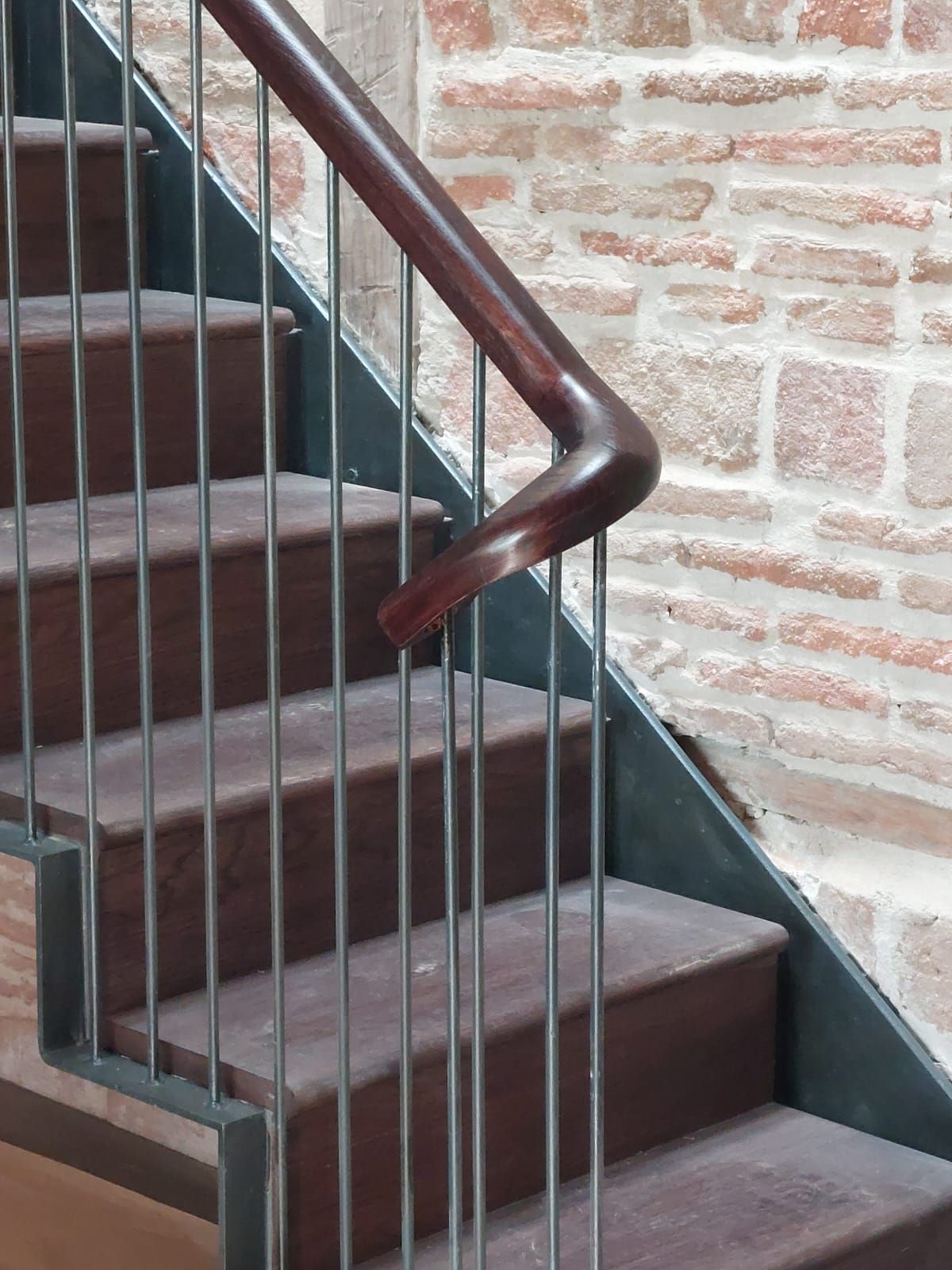 Una escalera con barandilla de metal y pasamanos de madera