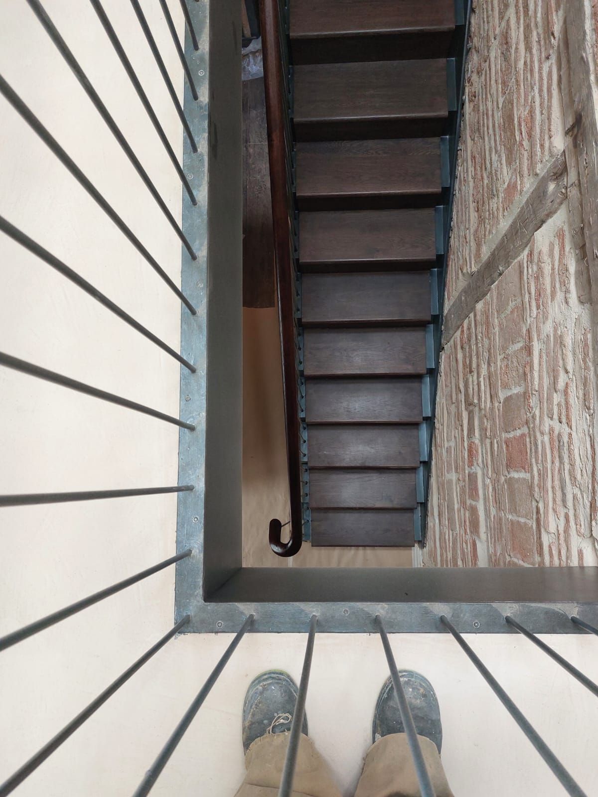 Una persona parada en un balcón mirando hacia abajo a una escalera.