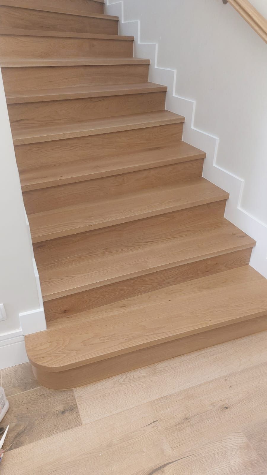 Una escalera de madera con barandilla blanca y suelo de madera.