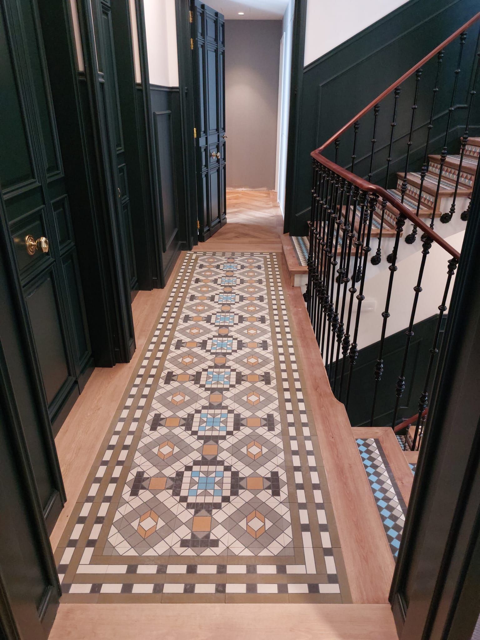 Un pasillo con una escalera y una alfombra en el suelo.