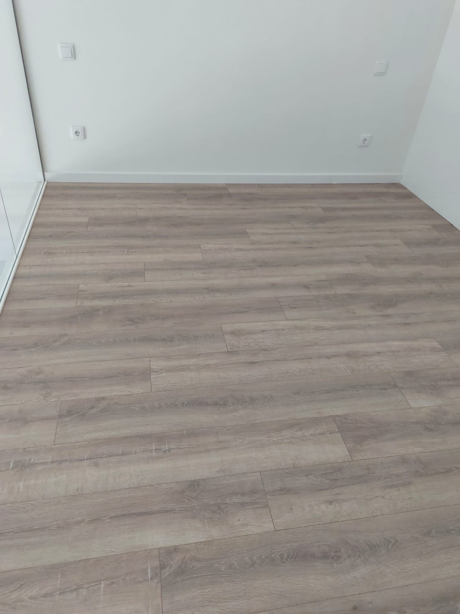Una habitación con suelo de madera y paredes blancas.
