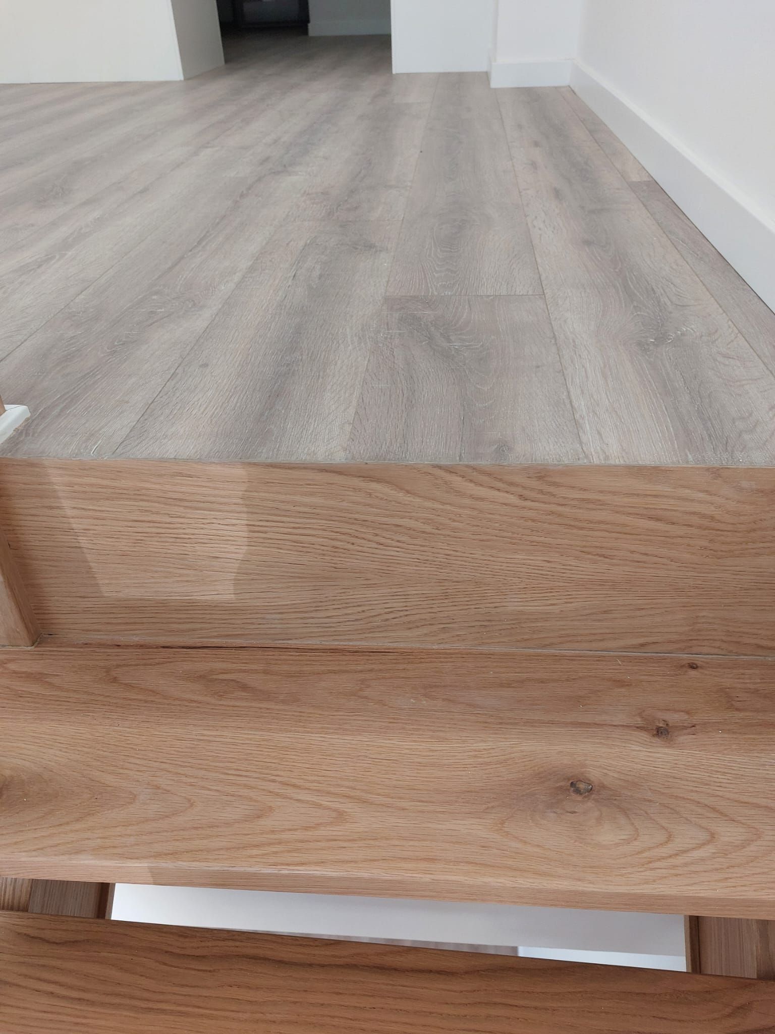 Un primer plano de un piso de madera al lado de una escalera de madera.