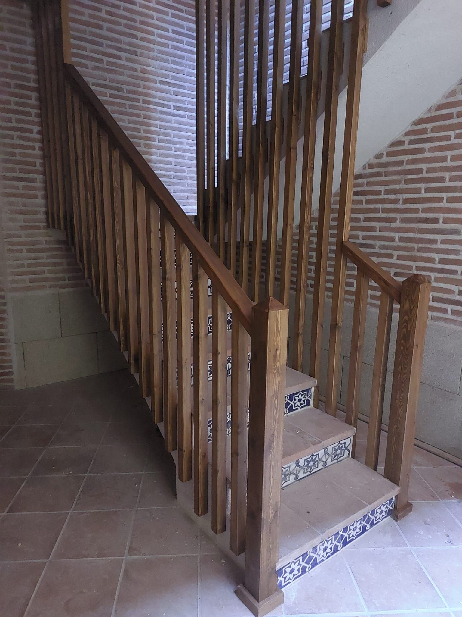 Una escalera de madera con una pared de ladrillos detrás.