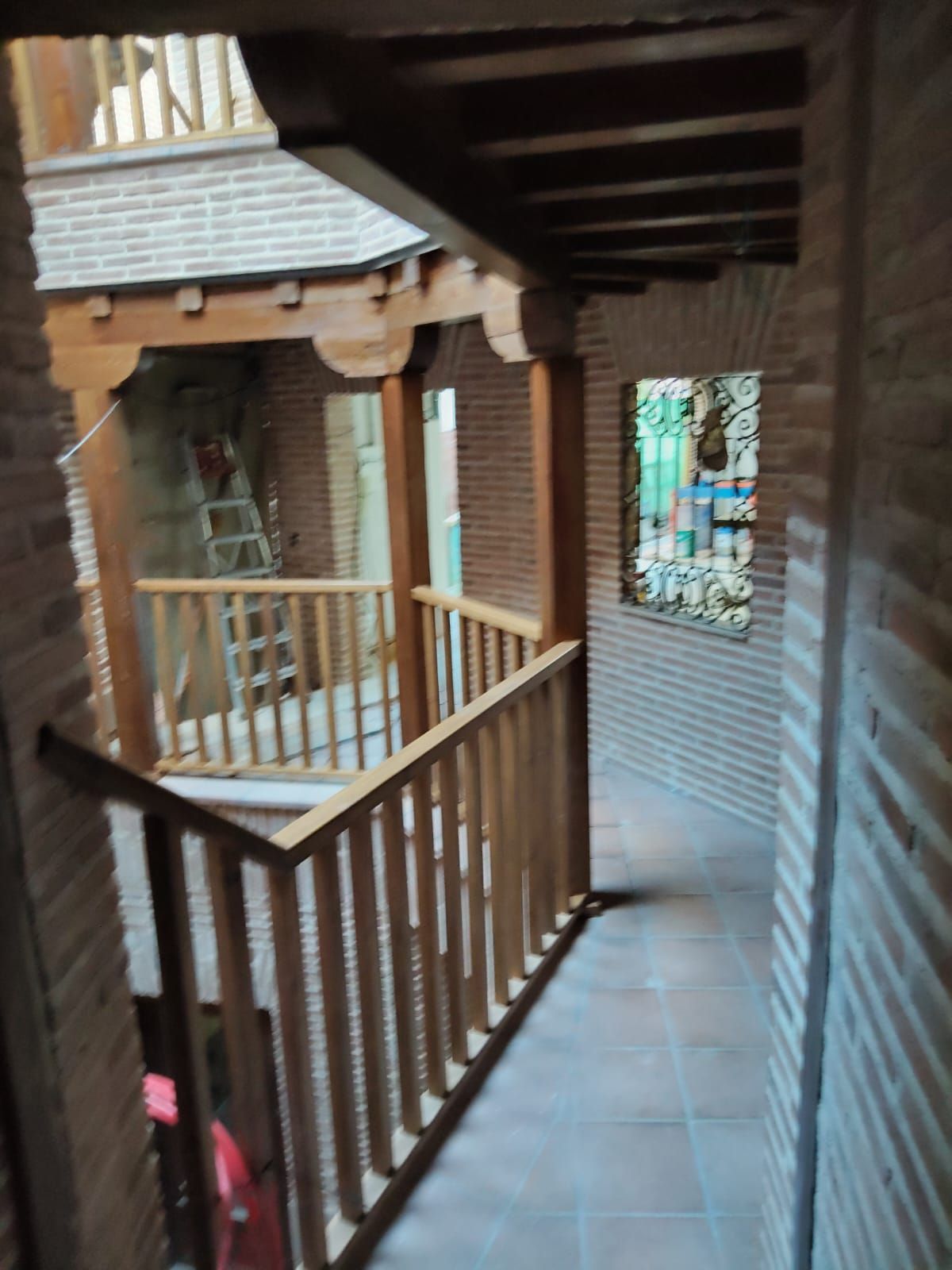 Un pasillo con barandilla de madera que conduce a un balcón.