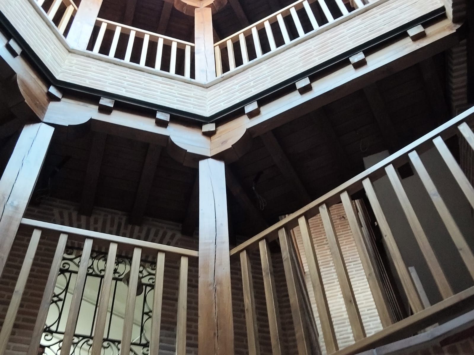 Mirando hacia arriba a una escalera con barandilla de madera