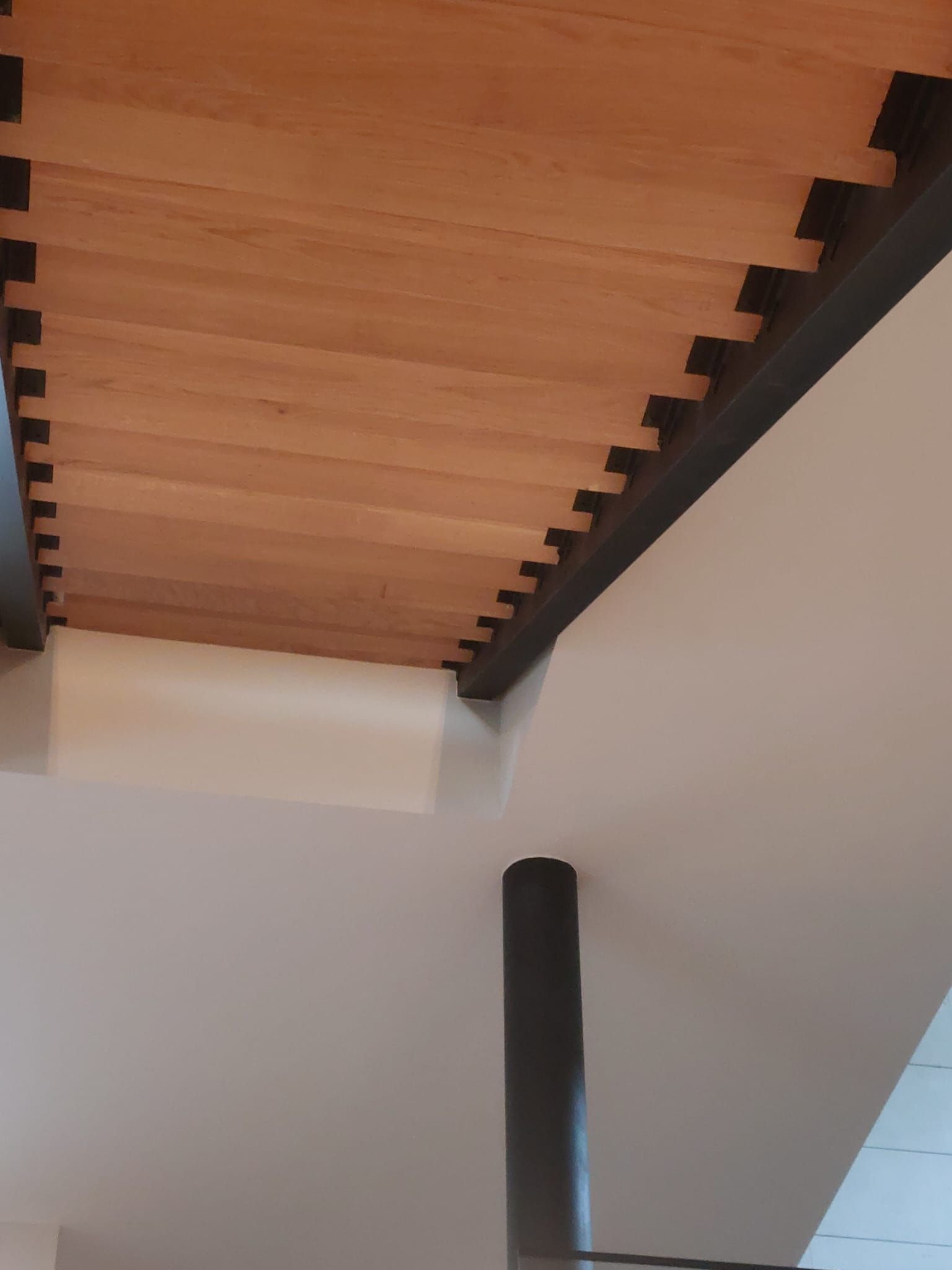 Un primer plano de una escalera de madera con barandilla negra.