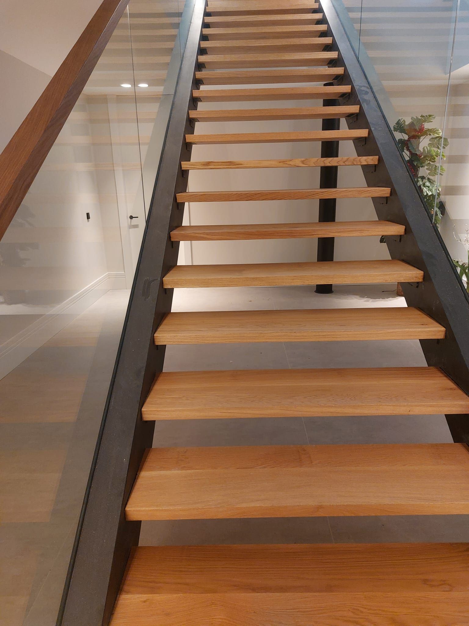 Una escalera con escalones de madera y barandilla de cristal.