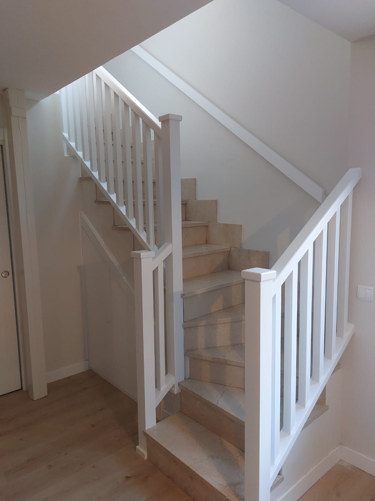 Una escalera con barandilla blanca y escalones de madera.