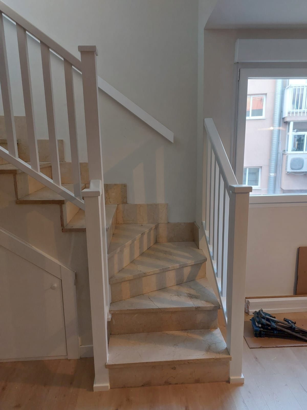 Una escalera con barandilla blanca y una ventana al fondo.