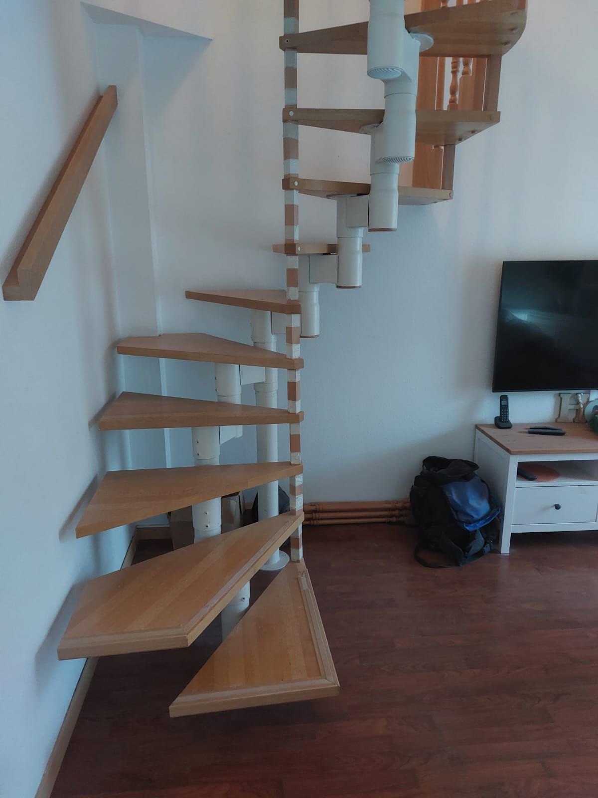 Una escalera de caracol en una sala de estar junto a un televisor de pantalla plana.