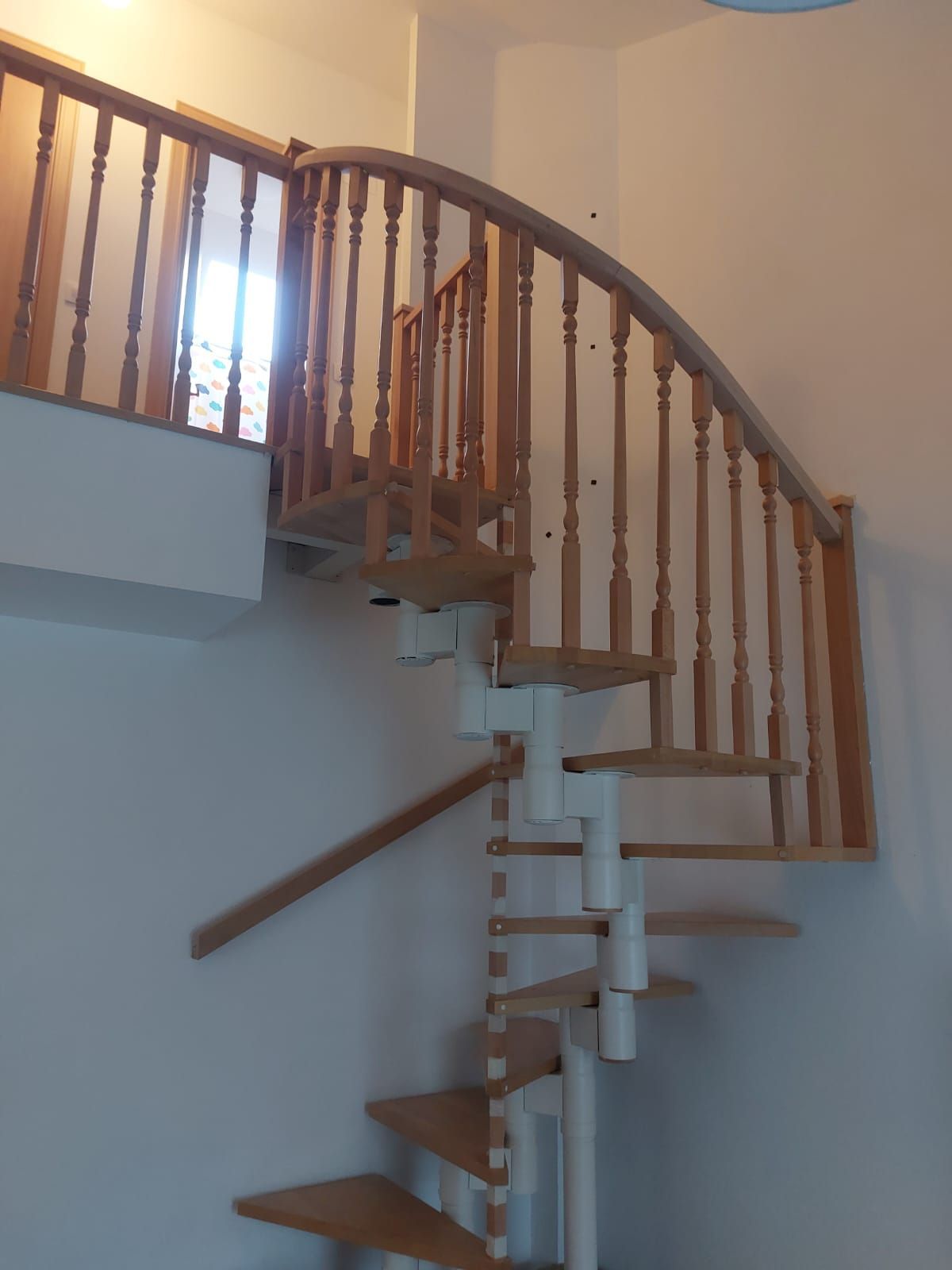 Una escalera de caracol con barandilla de madera que sube al segundo piso.