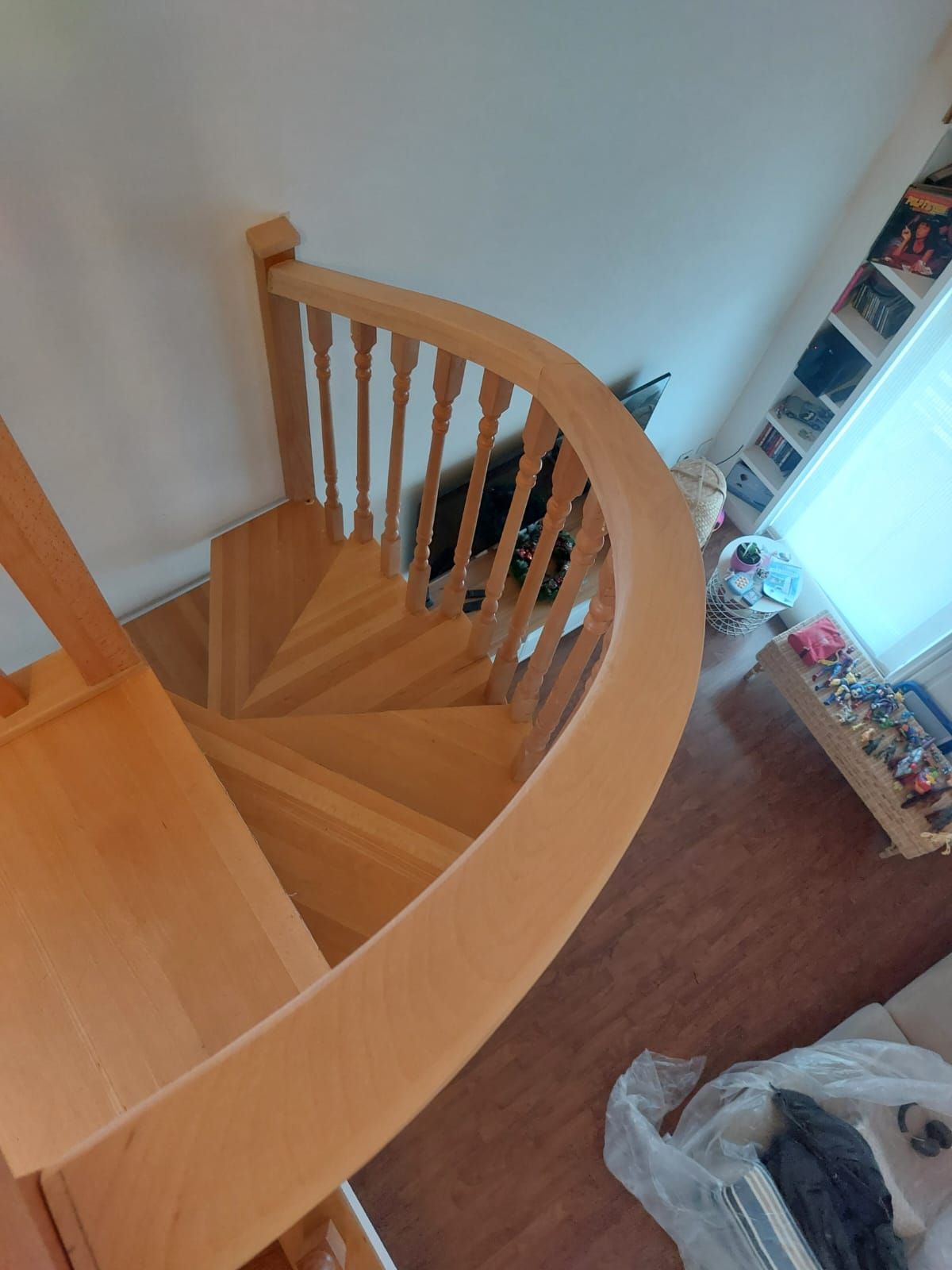 Una escalera de caracol de madera en una sala de estar con barandilla de madera.