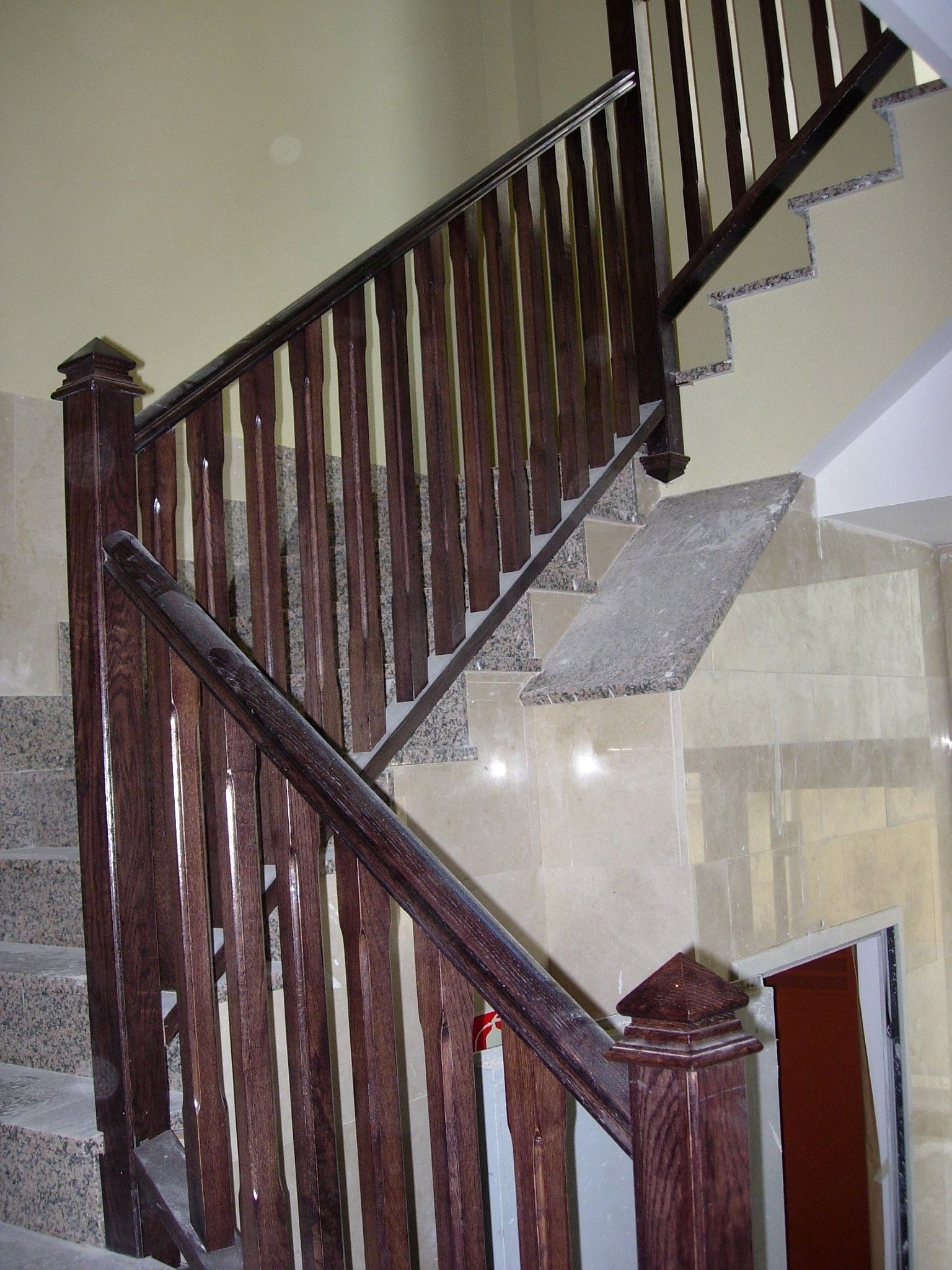 Una escalera con barandilla de madera y escalones de mármol