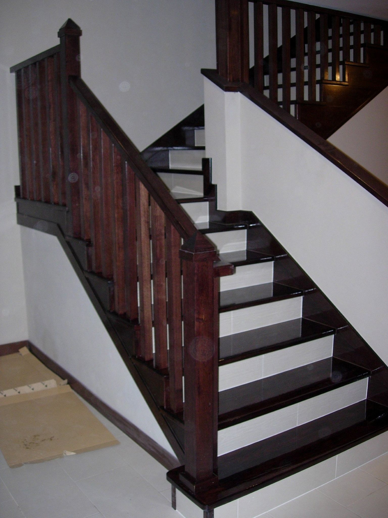 Una escalera con barandilla de madera y escalones blancos.