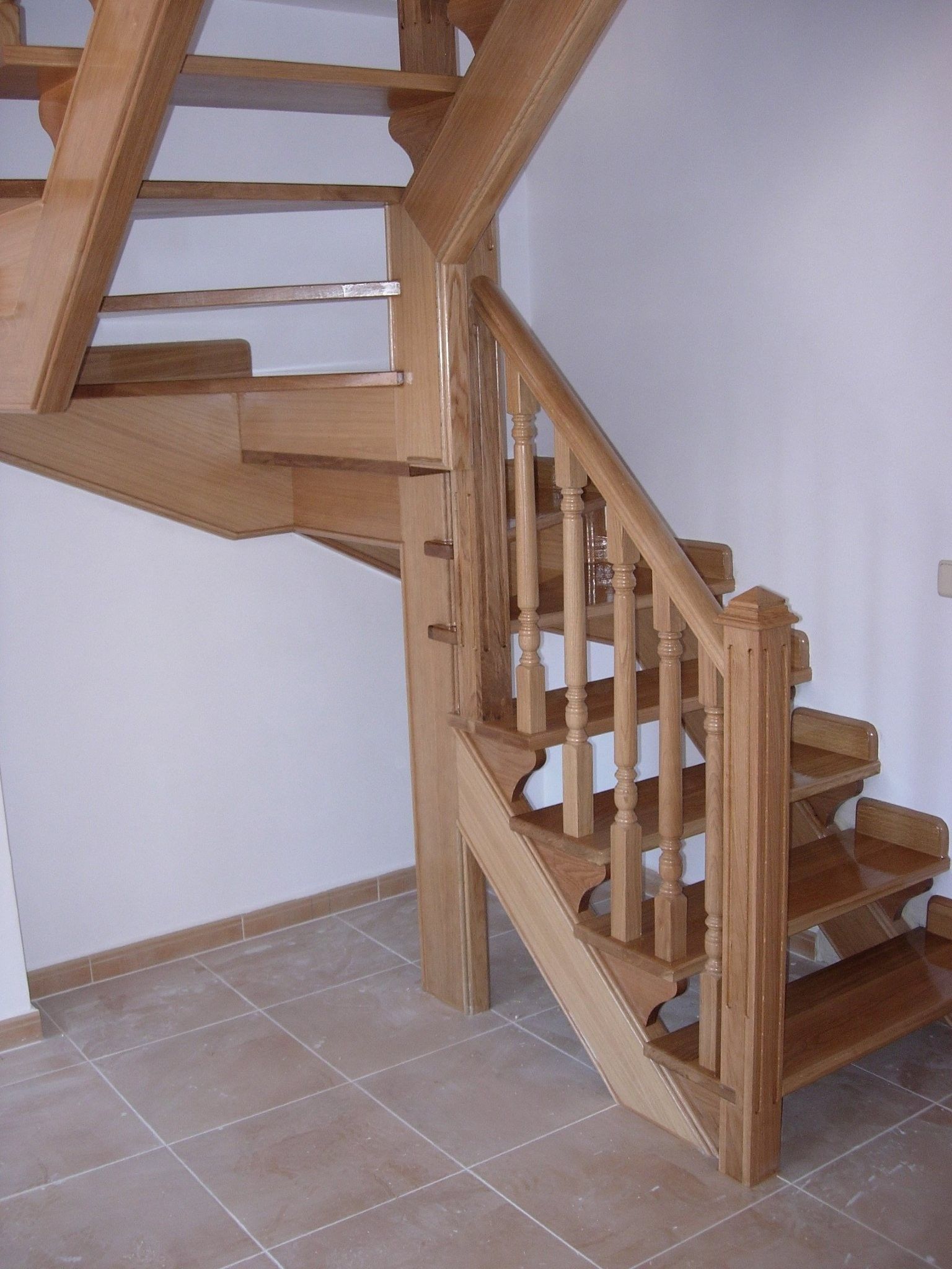 Una escalera de madera en una habitación con suelo de baldosas.