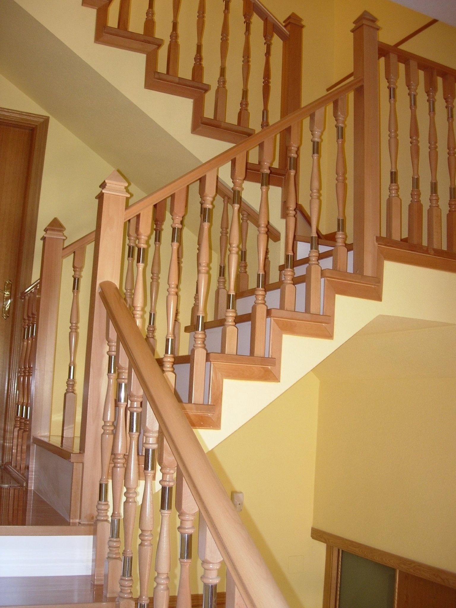 Una escalera de madera con paredes amarillas y una barandilla de madera.