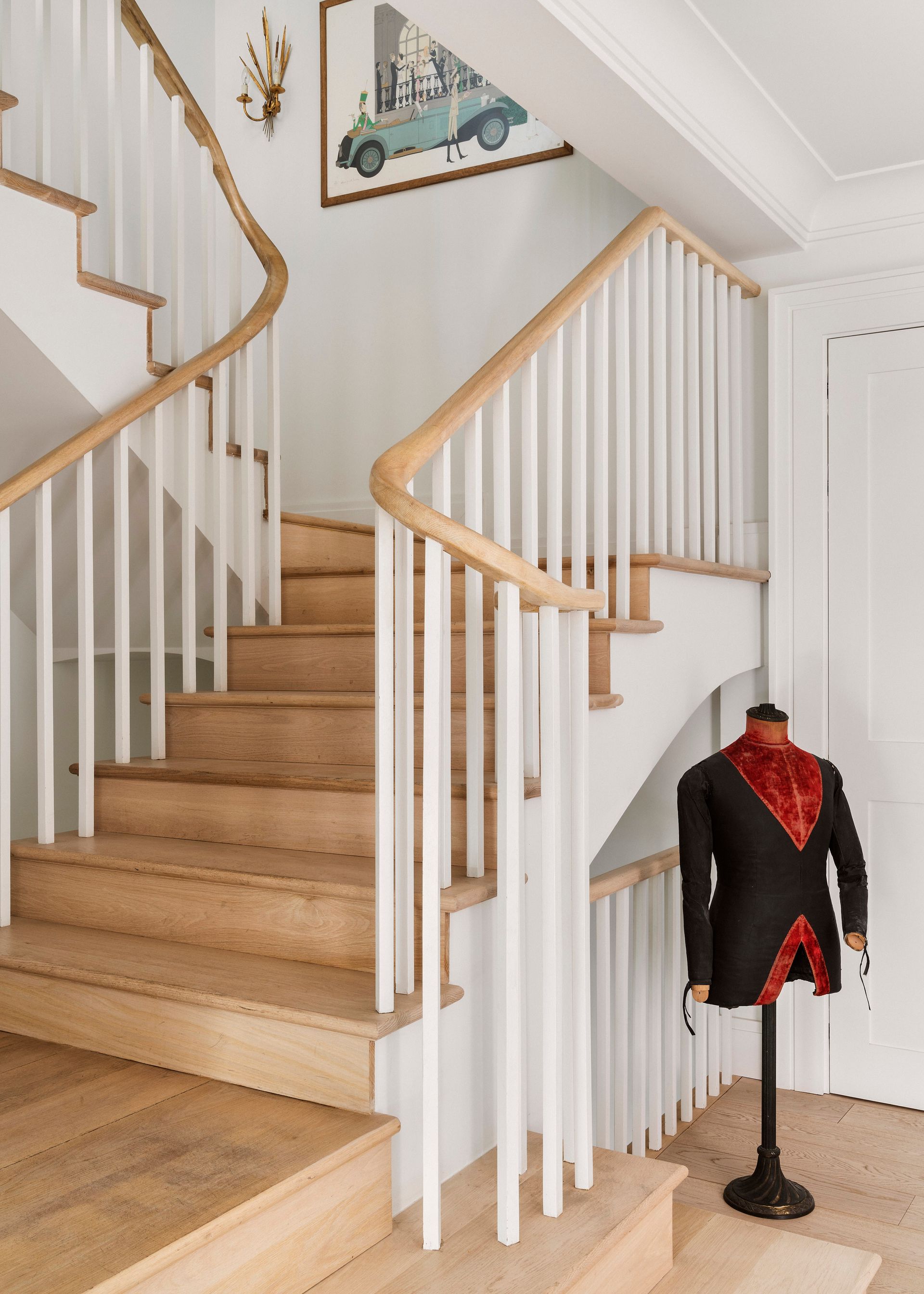 Una escalera de madera con barandillas blancas y un maniquí delante de ella.