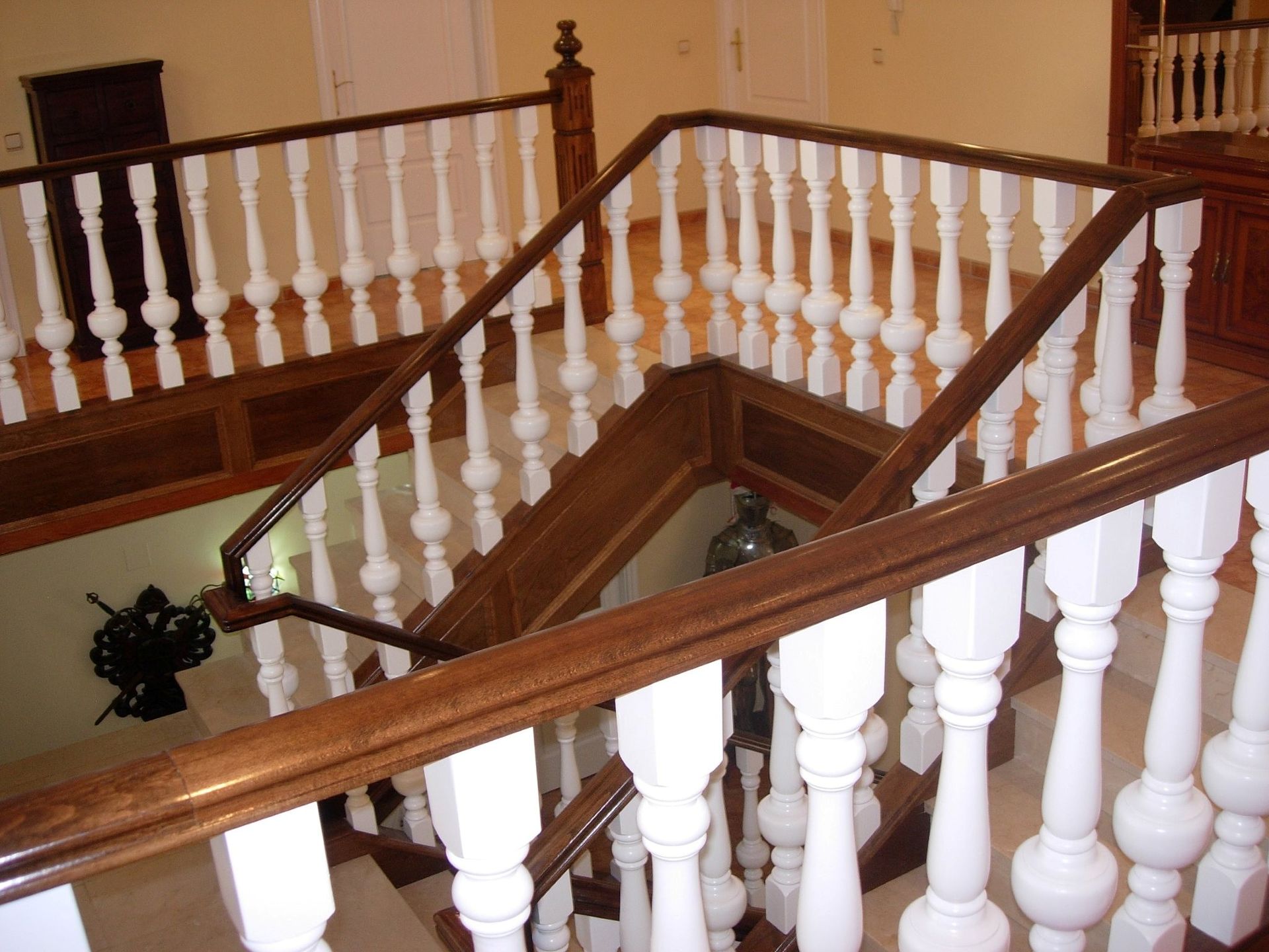 Una escalera con barandilla de madera y balaustres blancos.