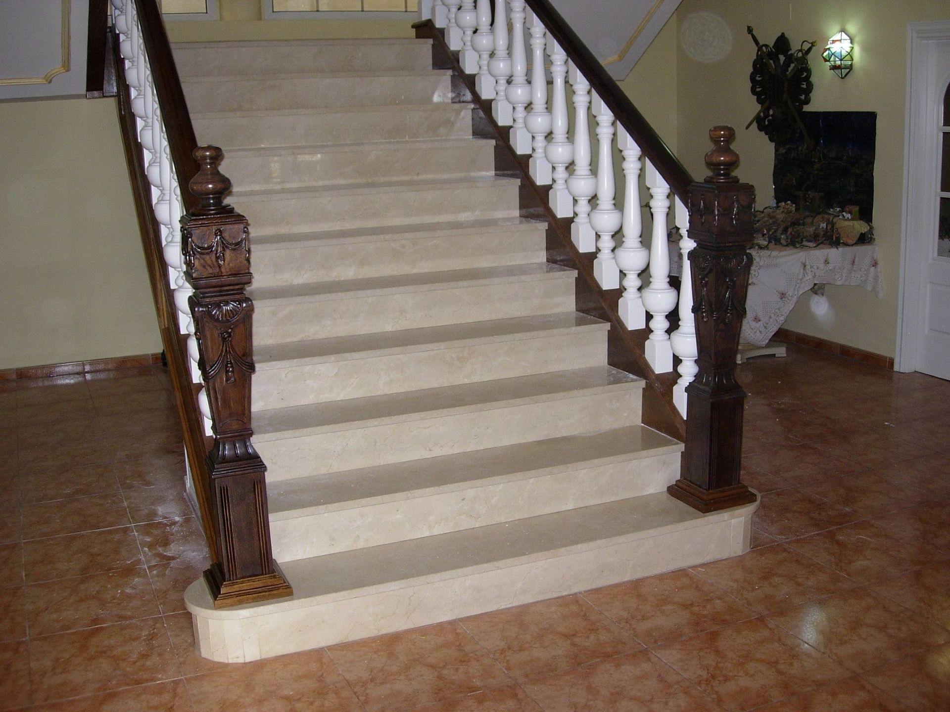 Una escalera con barandilla de madera y escalones blancos.