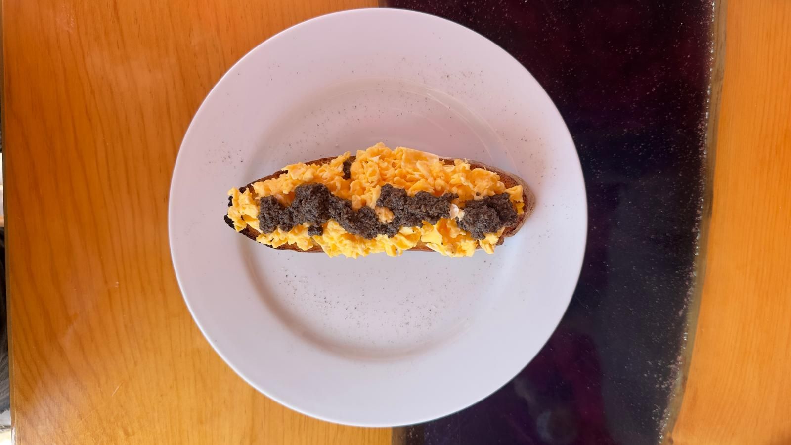 Manos emplatando un colorido plato de verduras en un plato blanco con un tenedor y una cuchara.