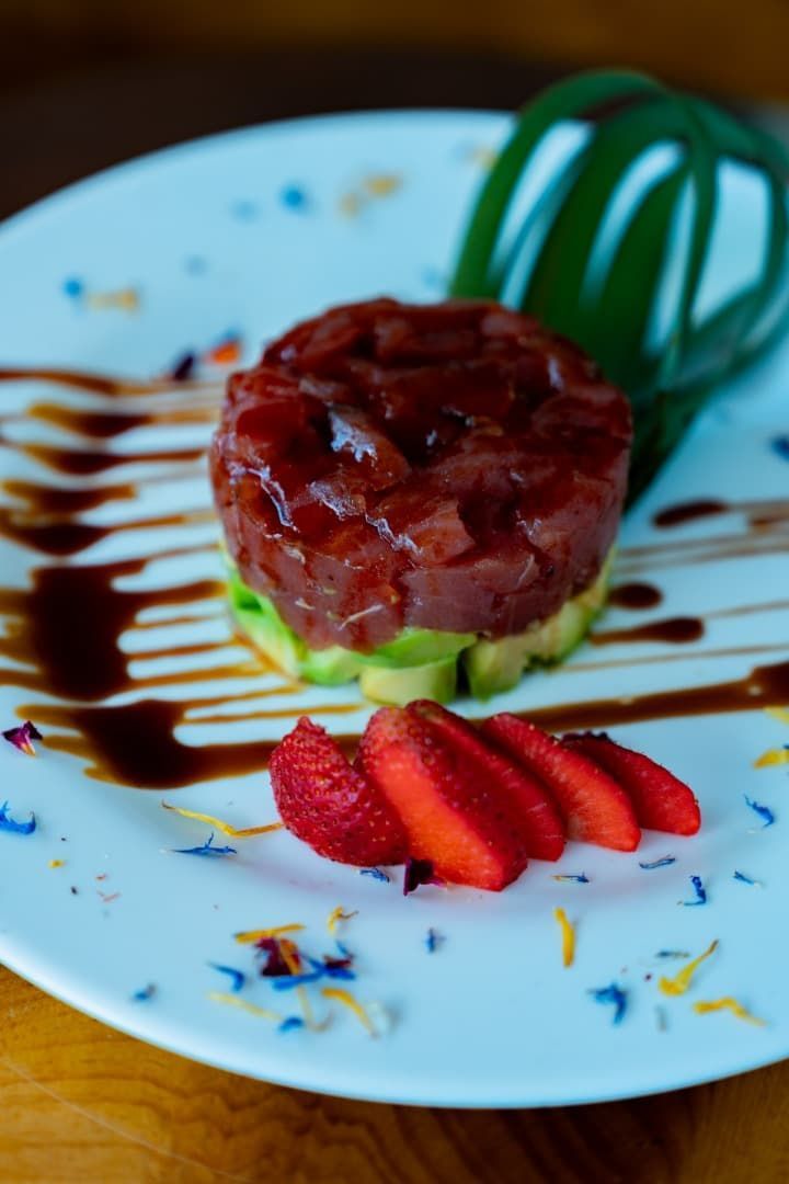 Tarta de postre con fresas, sirope de chocolate y menta en un plato blanco.