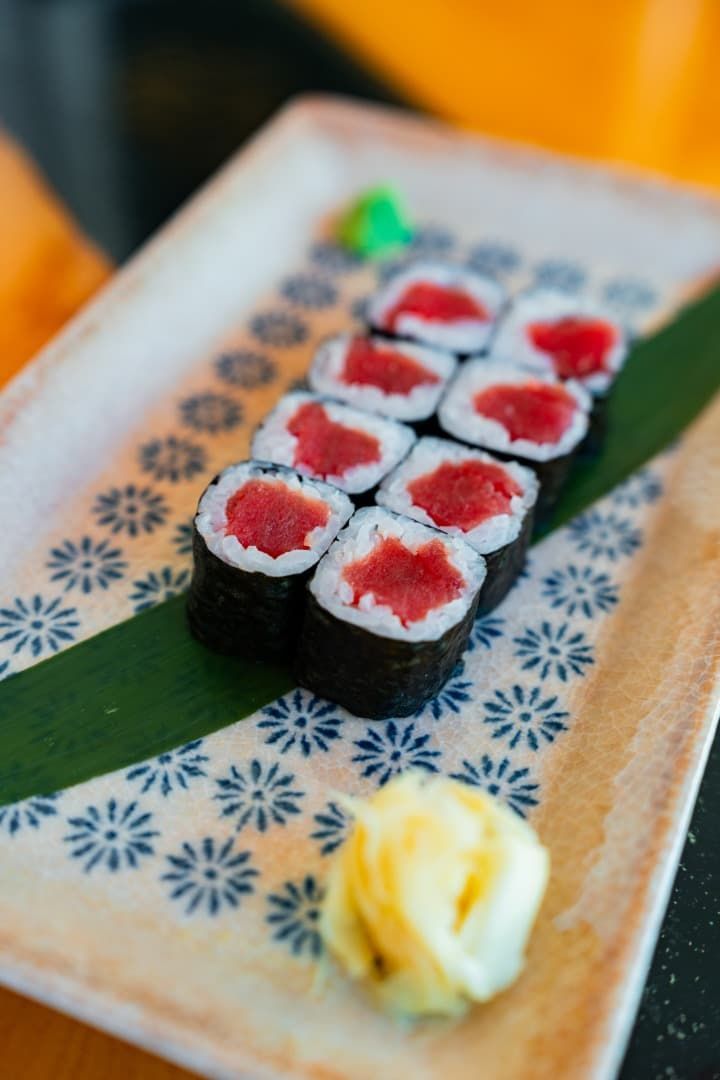 Rollos de sushi con relleno rojo en un plato estampado, con wasabi en primer plano.