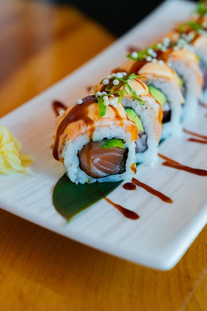 Una persona está comiendo sushi con palillos en un plato.