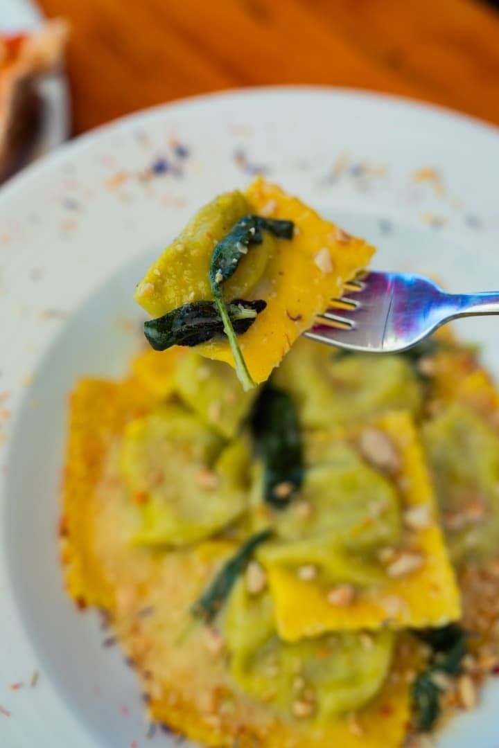 Raviolis con verduras servidos en un plato blanco.