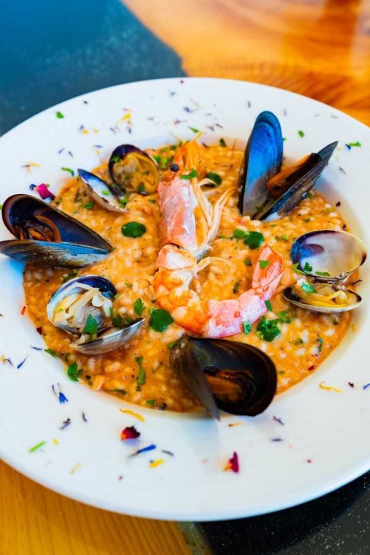 Risotto de mariscos con mejillones, camarones y almejas sobre un plato blanco.