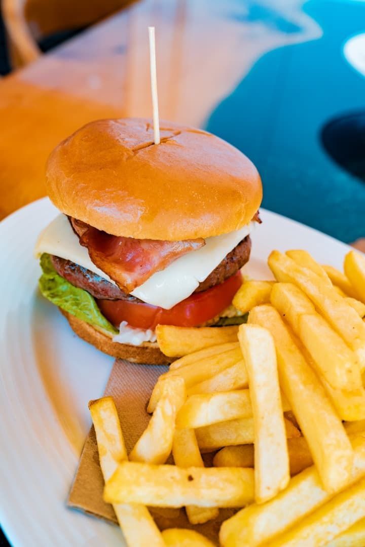 Hamburguesa y patatas fritas en un plato blanco con un palillo de dientes.
