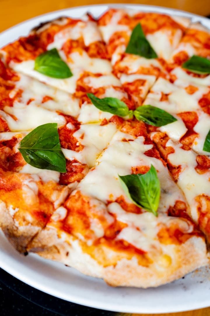 Una pizza con tomates, mozzarella y albahaca en un plato.