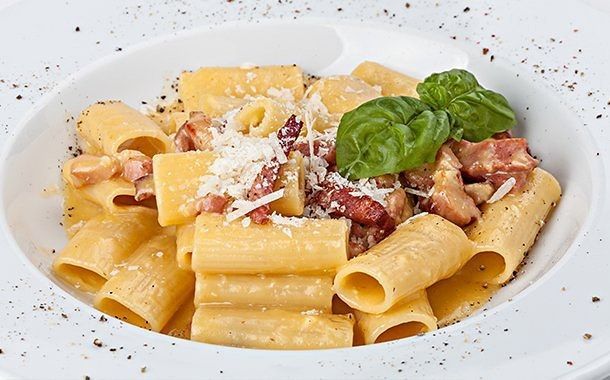 Un primer plano de un plato de pasta con tocino y queso.