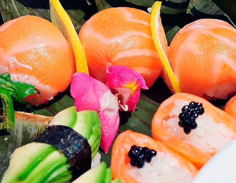 Un primer plano de sushi con aguacate y caviar en una hoja de plátano.