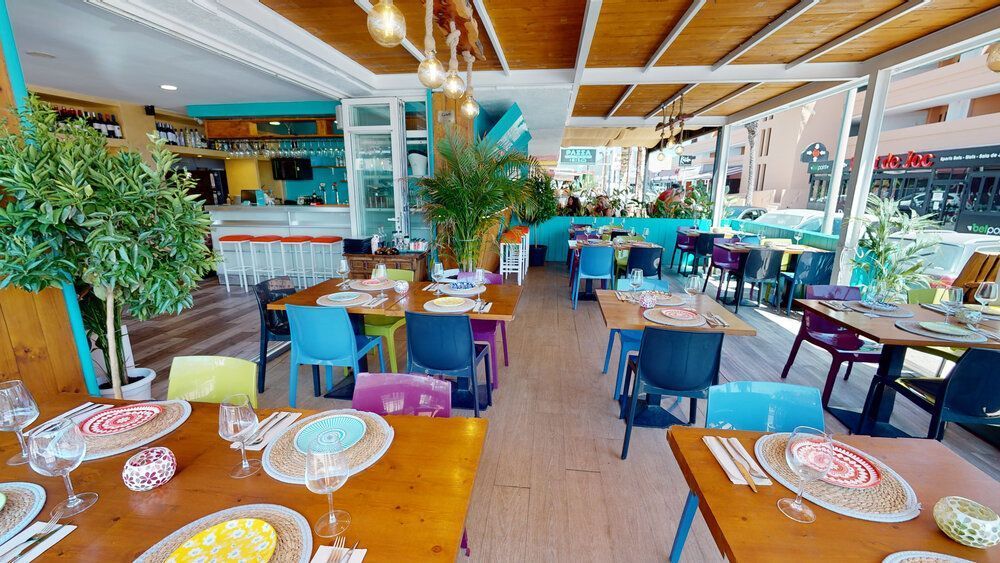 Un restaurante con muchas mesas y sillas y platos en ellas.
