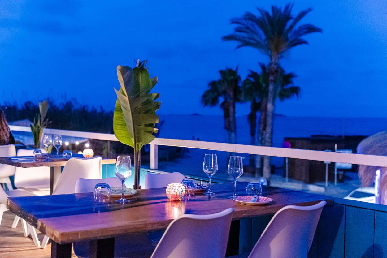 Un restaurante con vista al mar y palmeras.