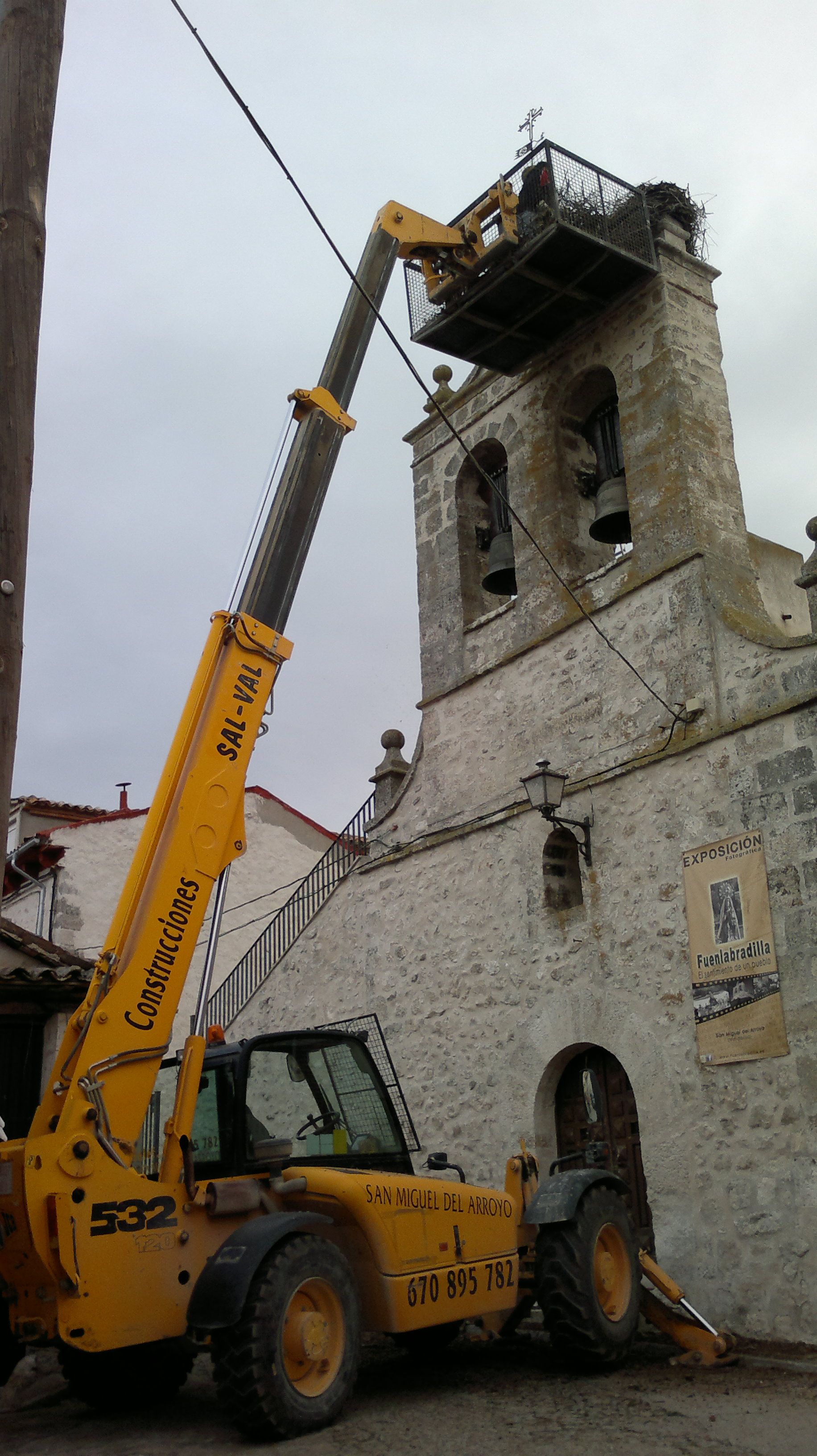 Un vehículo de construcción amarillo está estacionado frente a un edificio.