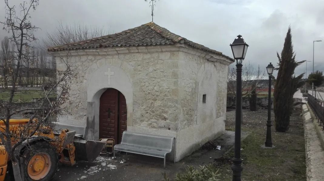 Un tractor está estacionado frente a un pequeño edificio blanco.