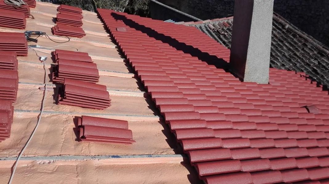 Un techo con tejas rojas y una chimenea encima.