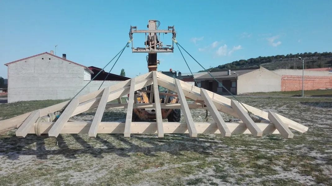 Una gran estructura de madera está siendo levantada por una grúa.